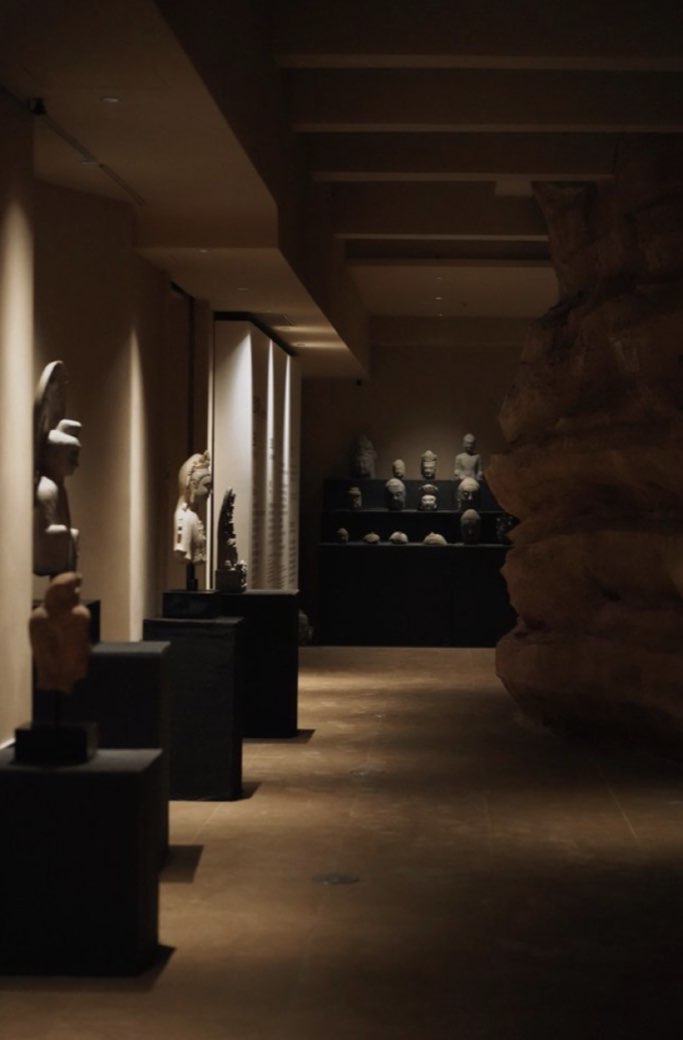 Stone heads on plinths beside a sandstone wall