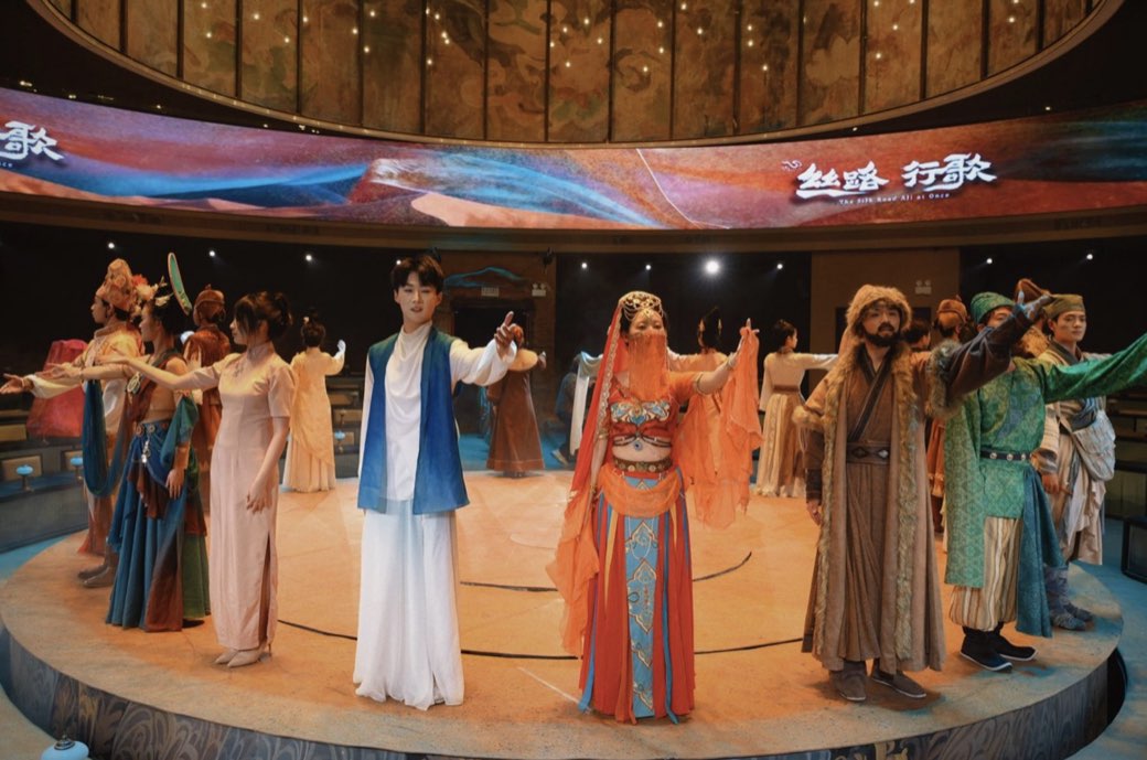 The company across the stage beneath the panoramic screen