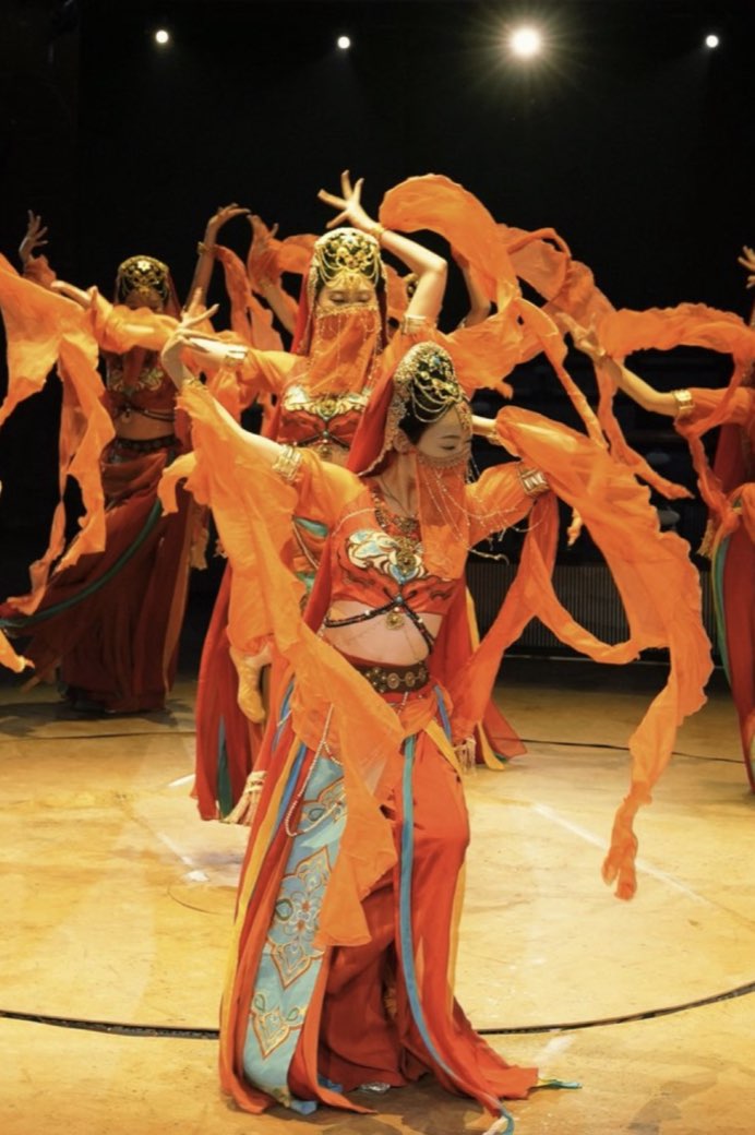 A ring of dancers, sleeves thrown outward